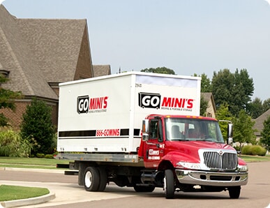 Go Mini's portable storage unit on a truck bed driving through a neighborhood